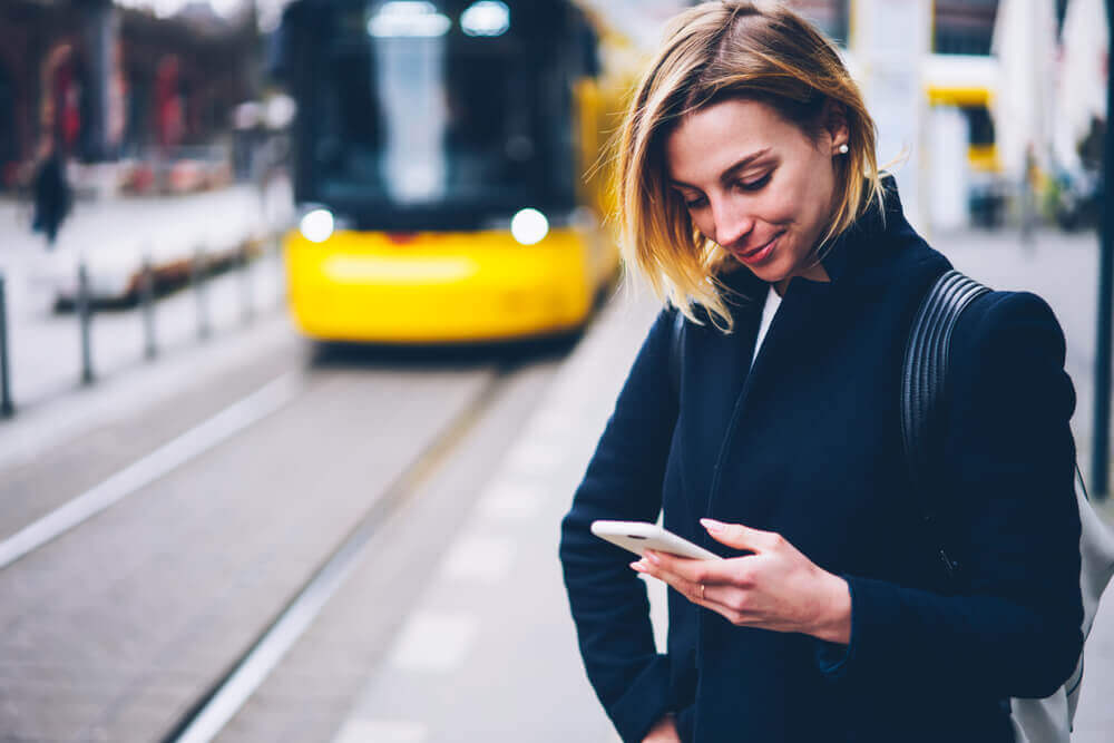 Woman looking at phone at tram station