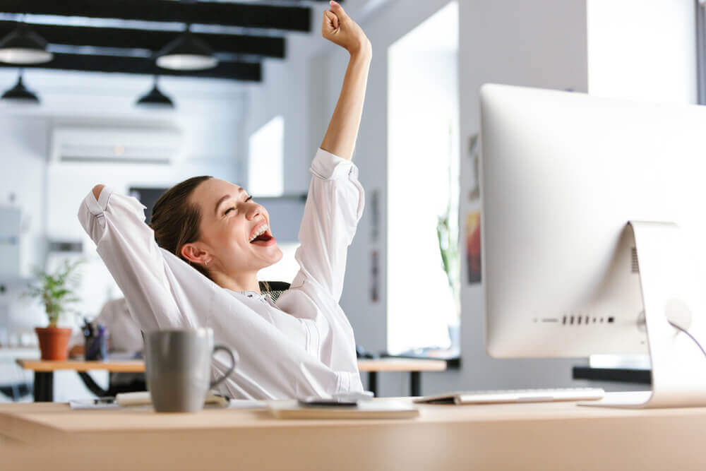 Woman smiling with arm stretched at desk at work
