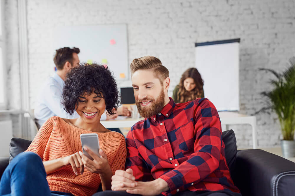 Two people looking at phone in office