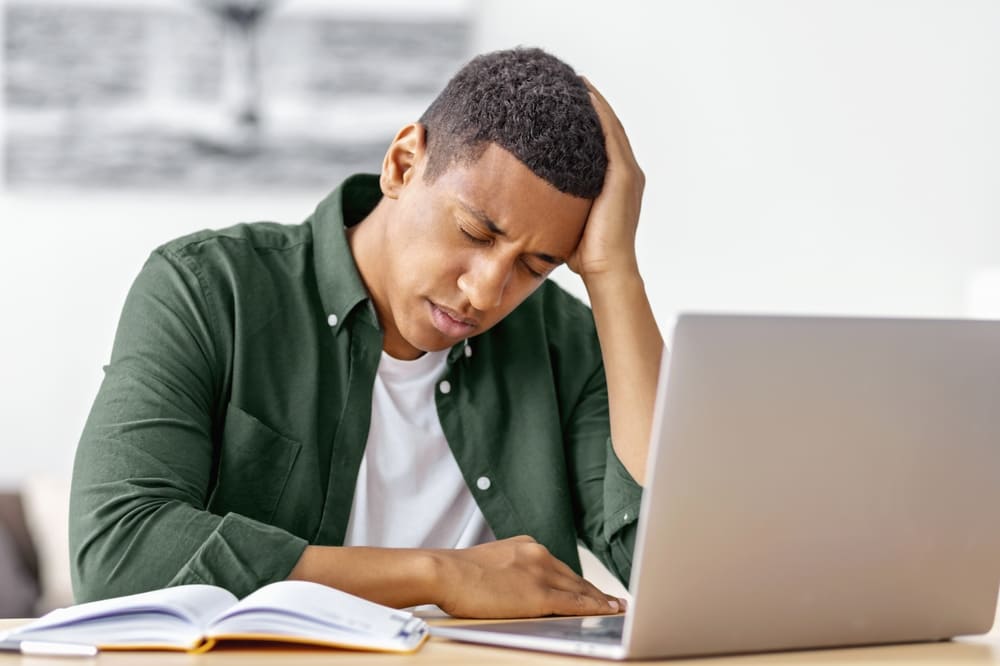 Man at desk with laptop experiencing burnout