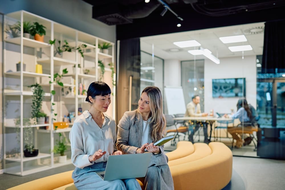 Two freelancers sitting and talking in a coworking space
