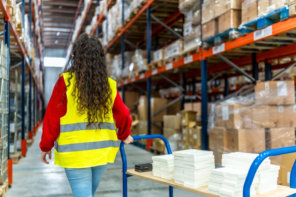 Woman wheeling packages in warehouse