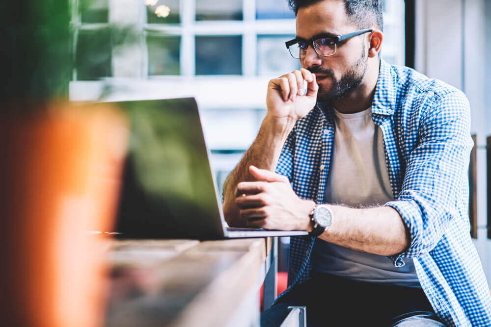 Man looking at laptop and thinking