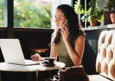 Woman on phone with laptop at cafe