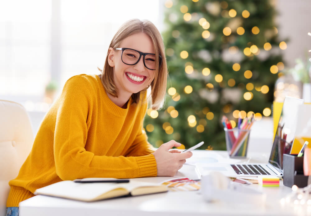 Woman at desk with Christmas tree in background