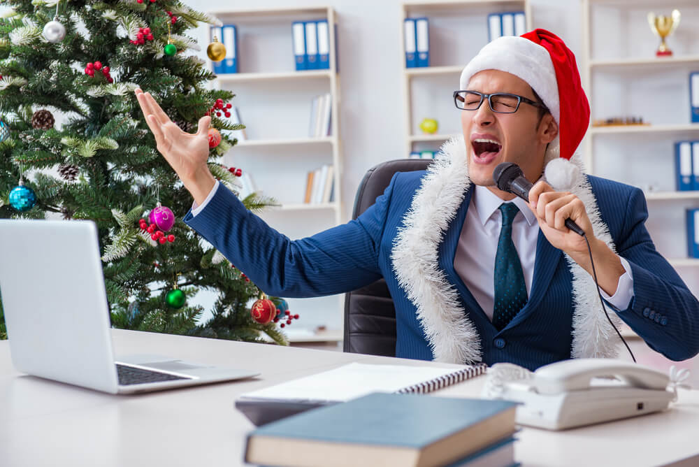 Man singing Christmas karaoke at office desk